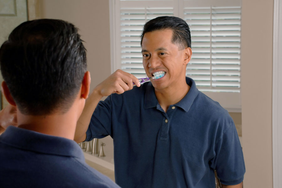 Man brushing teeth because of his dental insurance